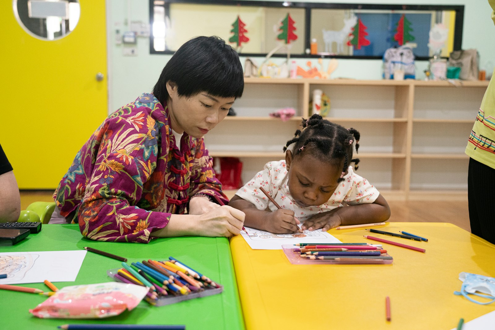 An educator drawing with a child at a classroom table